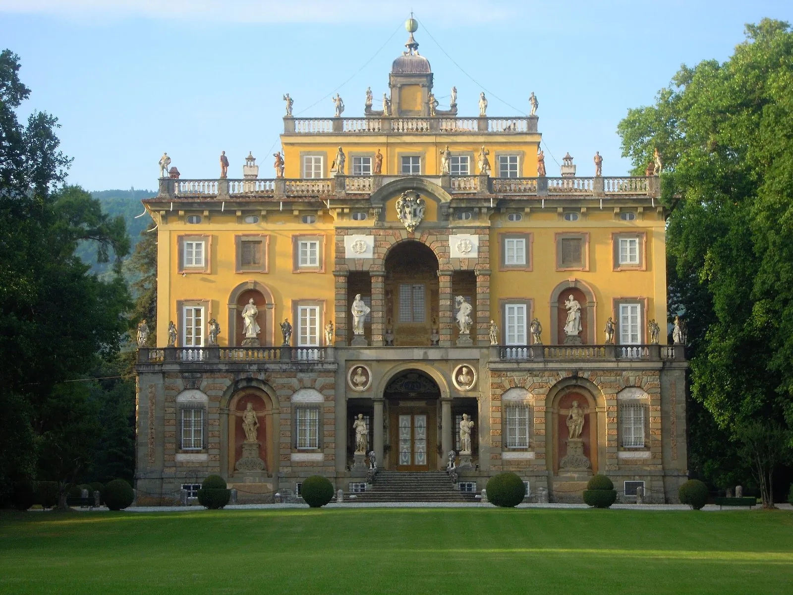 Facciata barocca gialla con statue di Villa Torrigiani a Camigliano, circondata dal parco